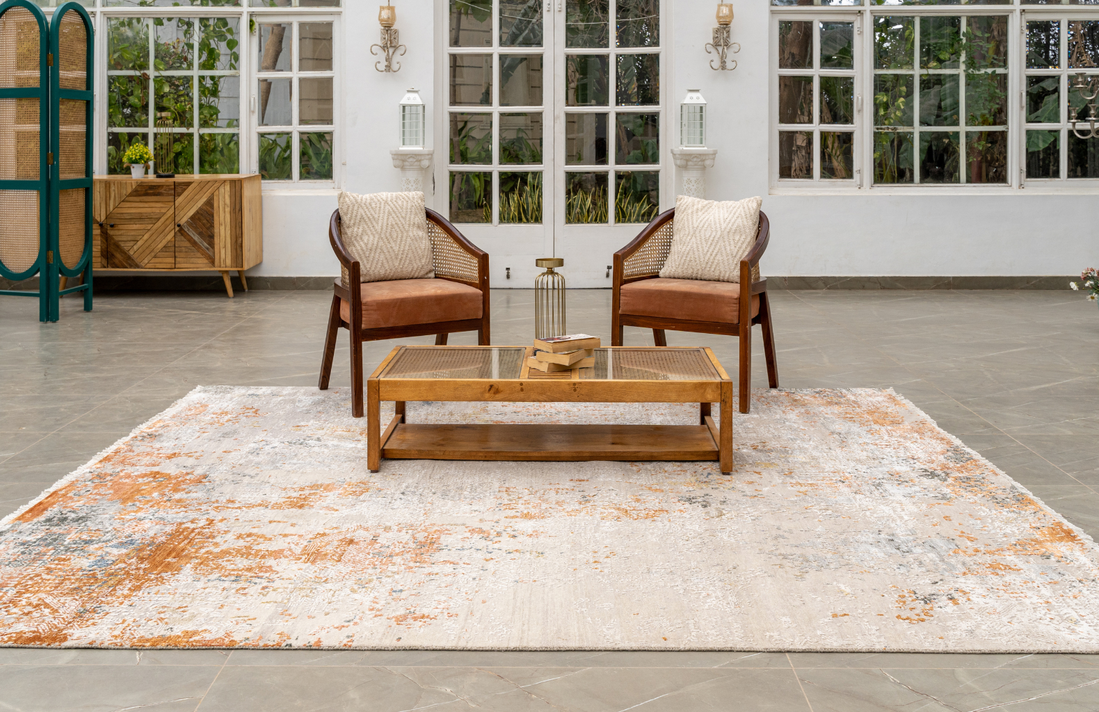 Modern living room with two wooden armchairs, a coffee table, and a textured neutral rug with warm orange accents.