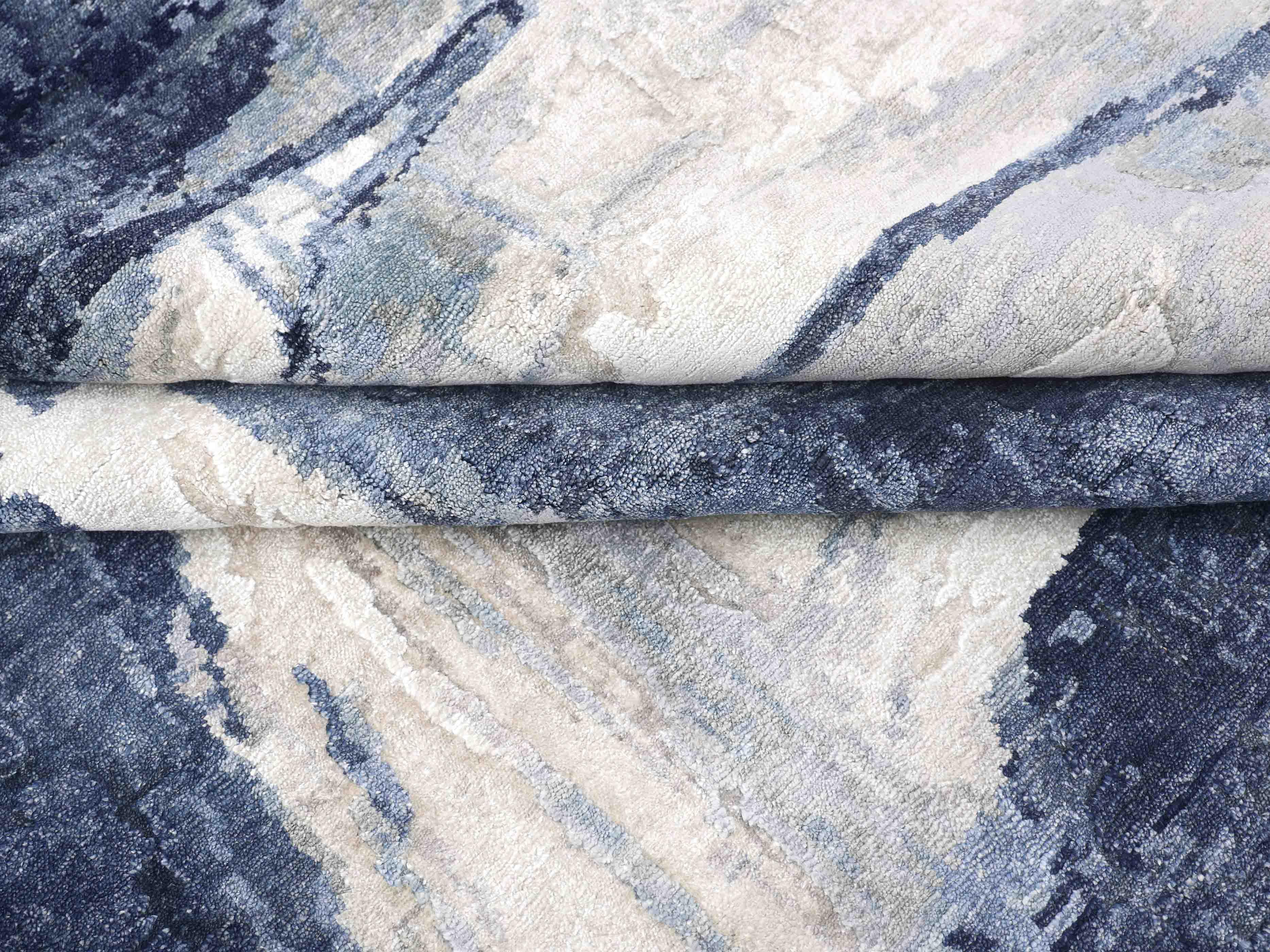 Luxury abstract rug with blue and beige tones, showcasing intricate woven texture and elegant design.