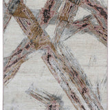 Abstract patterned rug featuring intersecting lines in earthy tones of brown, pink, and gray on a light beige background. The design appears dynamic and textured.