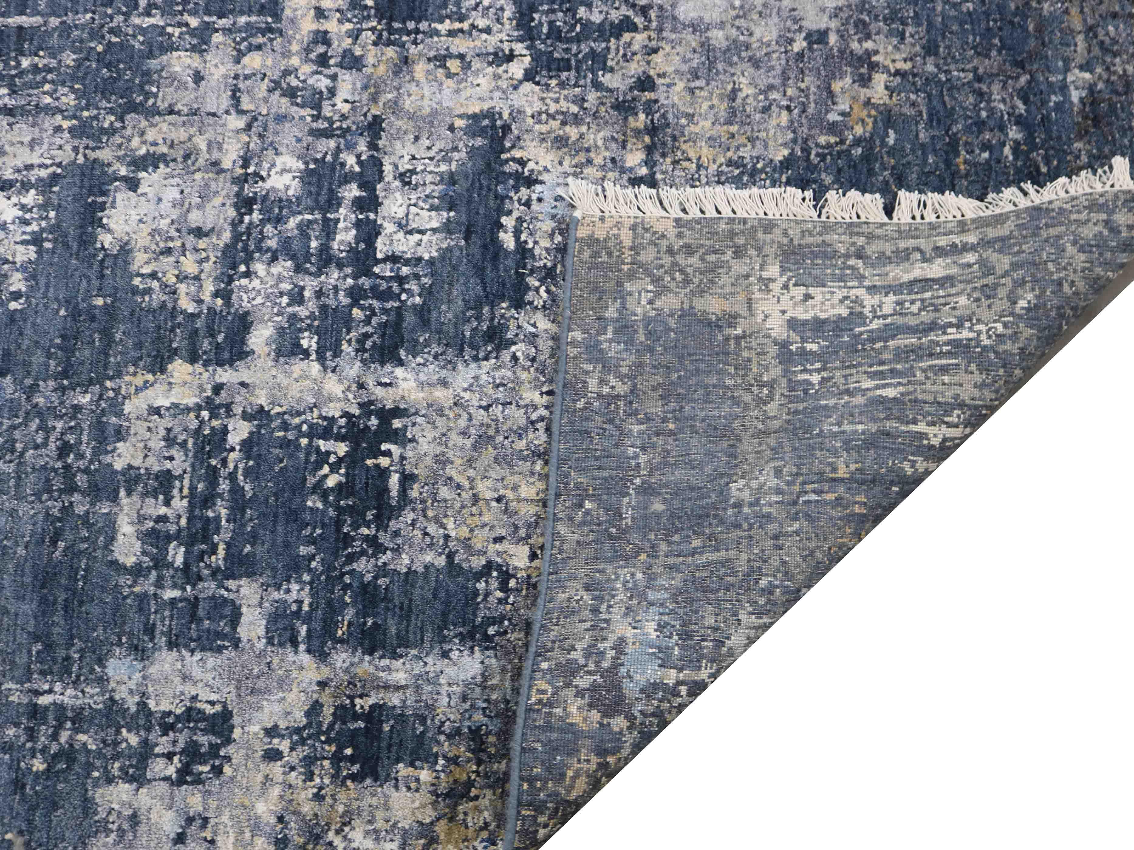 Luxury abstract rug with distressed blue and gold pattern, fringed edge, and elegant texture