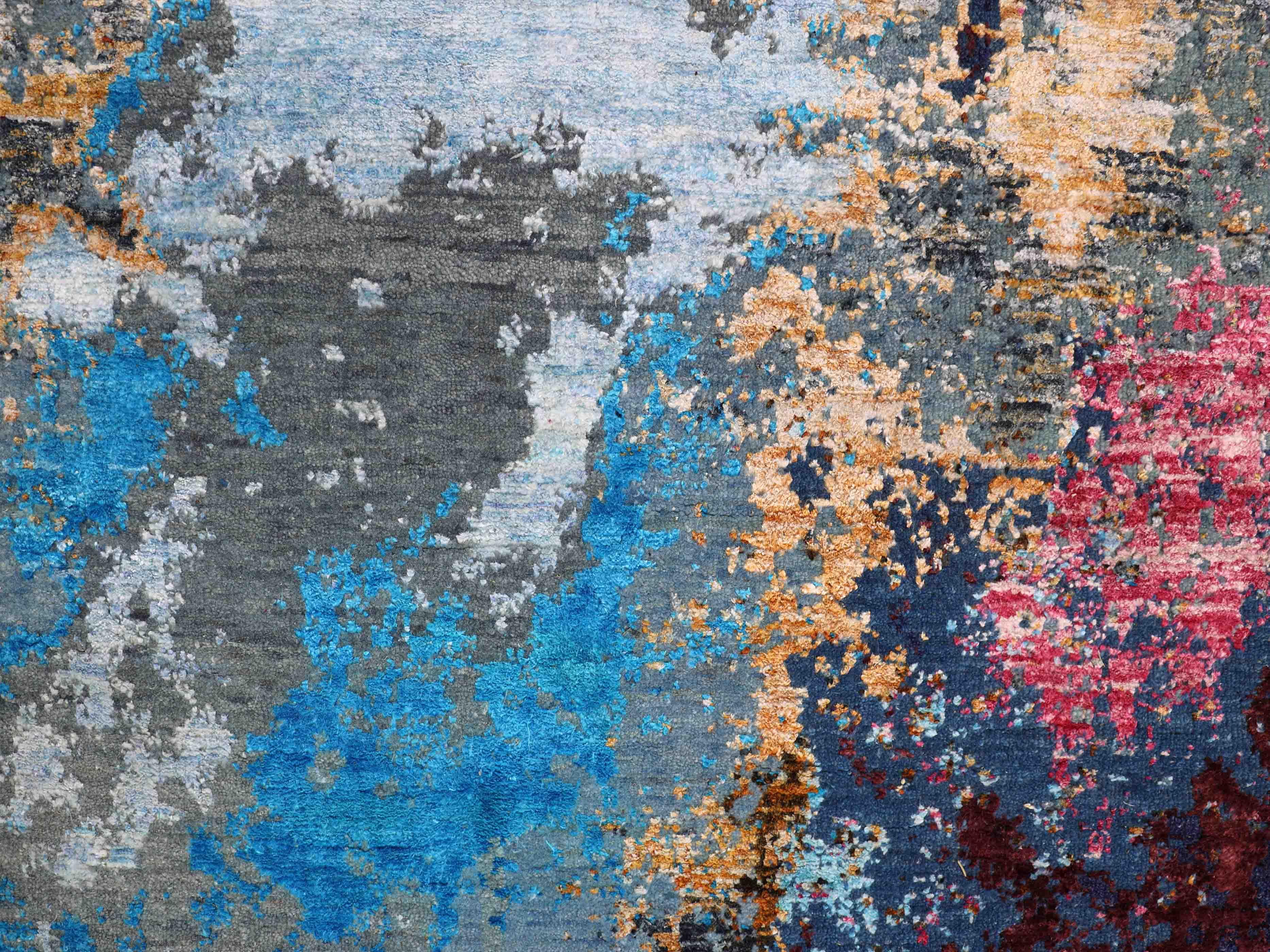 Abstract luxury rug with vibrant blue, pink, and gold accents on a gray textured background