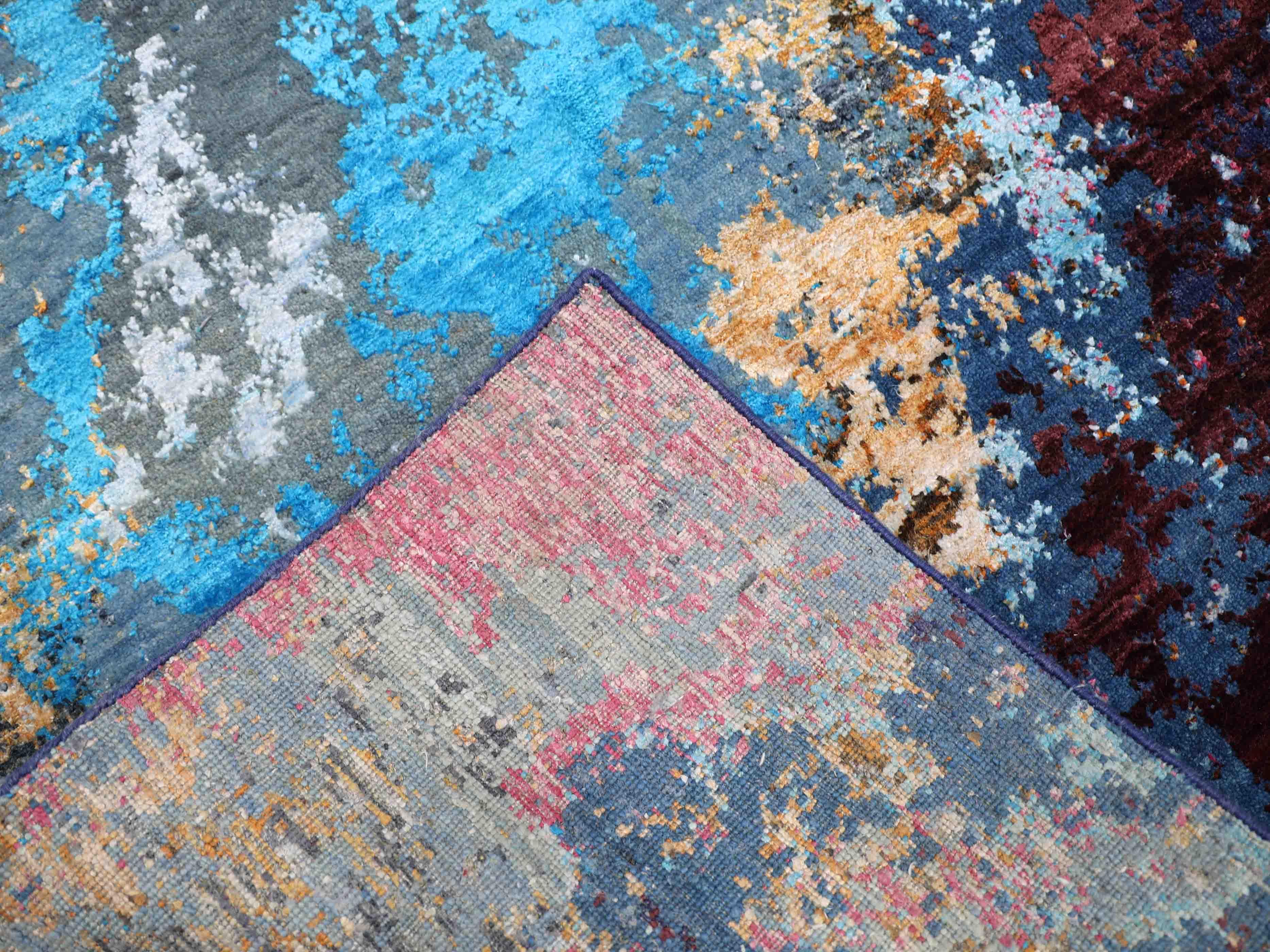 Abstract multicolor luxury rug with blue, red, and pink patterns, showcasing intricate woven texture and vibrant design.
